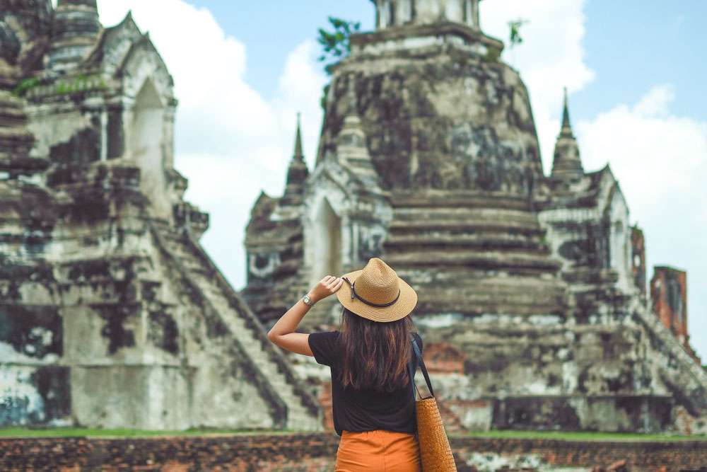 une touriste prend des photos dans un temple à Ayutthaya